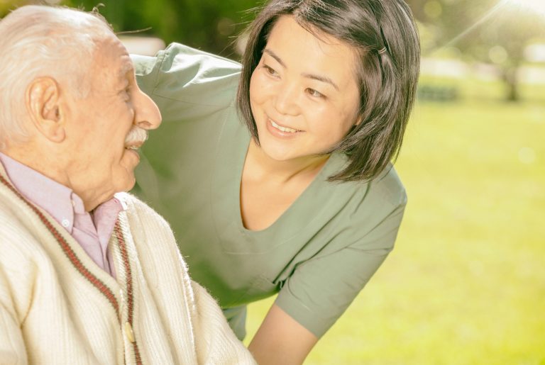 Asian female doctor playing and smiling with mature elderly man in the hospital garden.  Retirement community concept